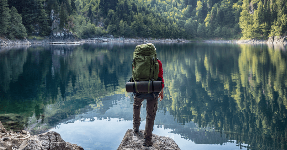 Person on holiday with a back pack by a lake.