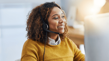 Happy woman wearing a headset and a yellow jumper.